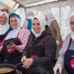 Frauen bei der Essenszubereitung im Zelt