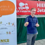 Portrait: Stammzellenspender mit Wattestäbchen und NKR Plakat